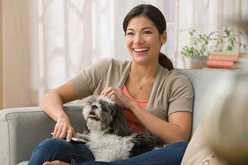 Woman holding her dog on a couch