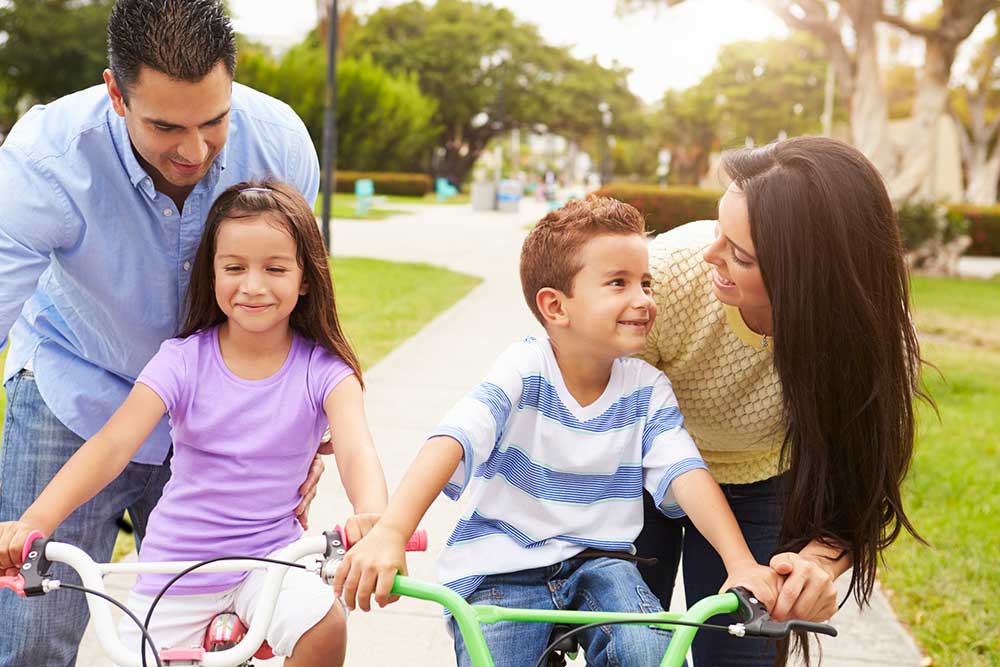 Parents teaching their 2 children how to ride a bike