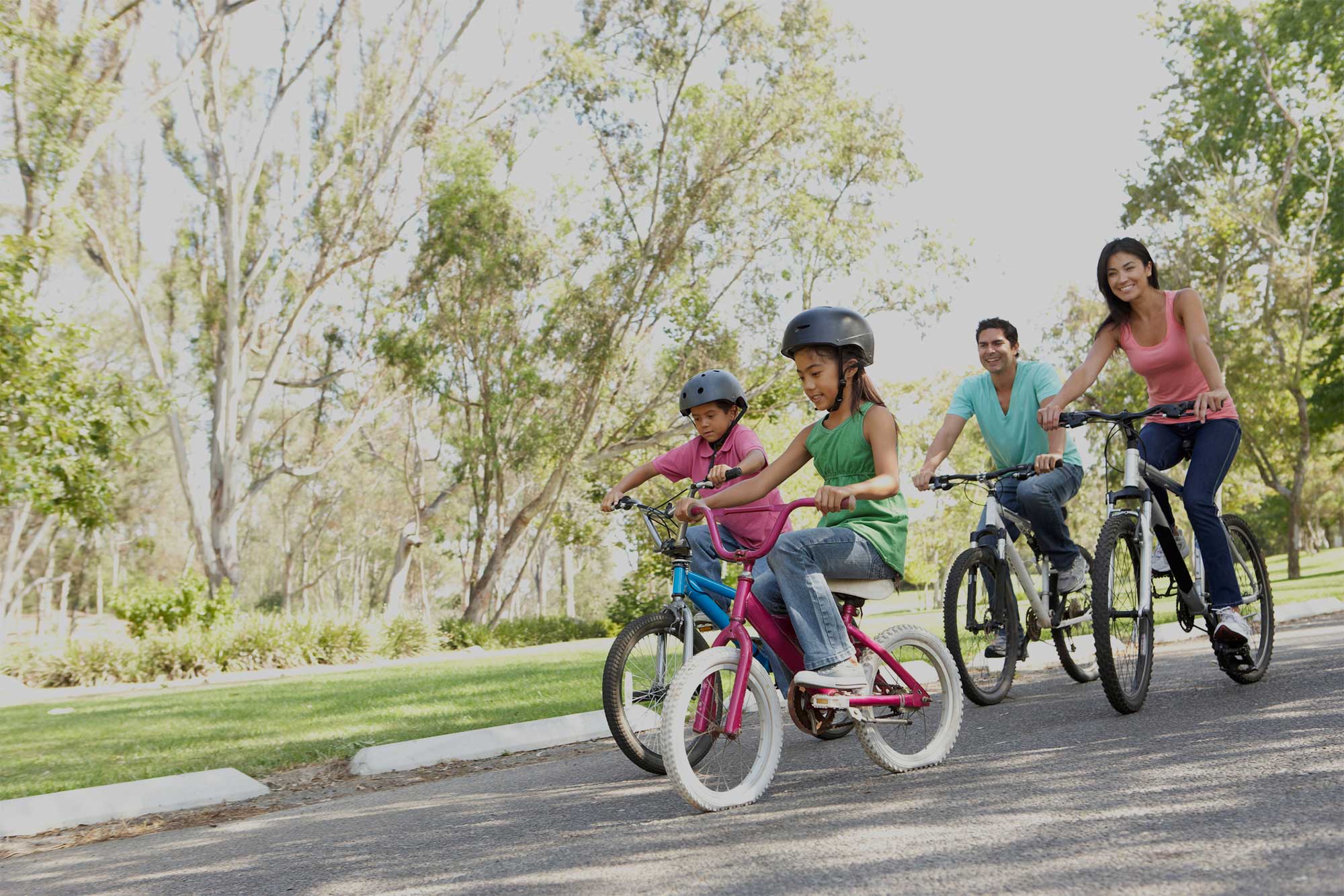 Family on bicycles riding through the park