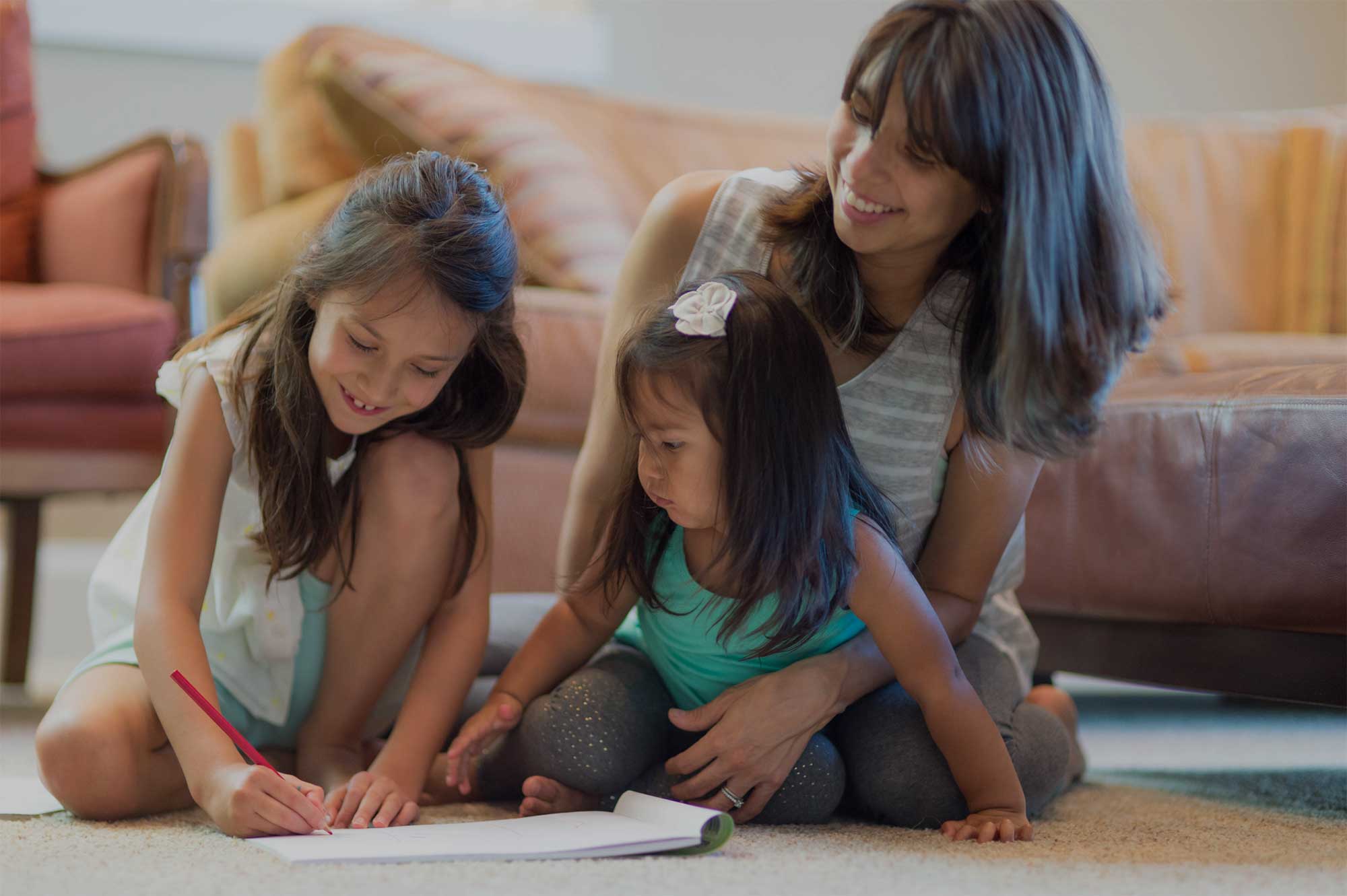 Women and her 2 children sitting on living floor drawing